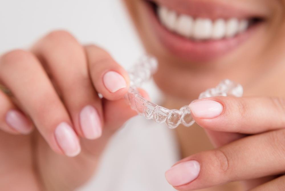 patient holding clear plastic aligner | invisalign dedham ma