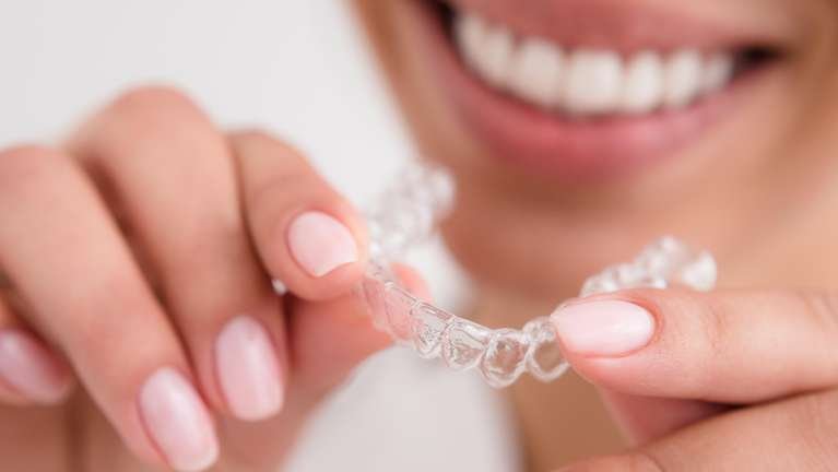 Invisalign Dedham | patient holding clear aligner